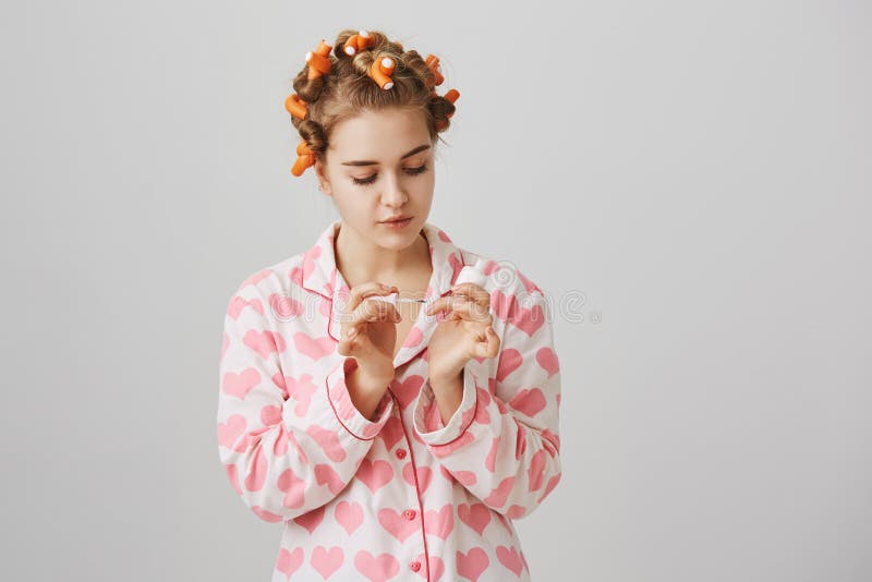 Милая и блестящая женщина в curlers и pyjamas волос с сердцами, крася ногтями пока находящся над серой предпосылкой девушка стоковая фотография rf Милая и блестящая женщина в curlers и pyjamas волос с сердцами, крася ногтями пока находящся над серой предпосылкой девушка стоковая фотография rf