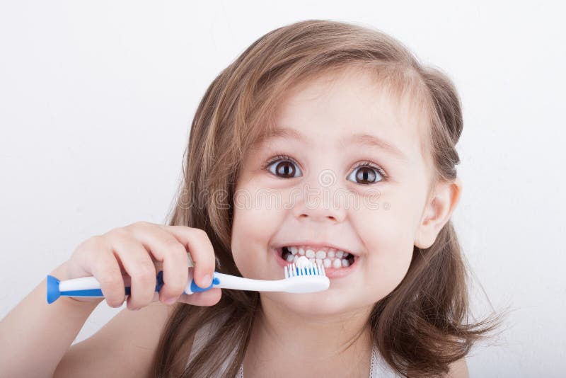 Cute little girl brushing his teeth. Looking at camera. Portrait. Only face and hand with toothbrush. Cute little girl brushing his teeth. Looking at camera. Portrait. Only face and hand with toothbrush