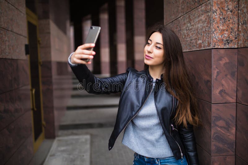 Милая молодая женщина имея прогулку и делая selfie около здания на улице стоковые фотографии rf