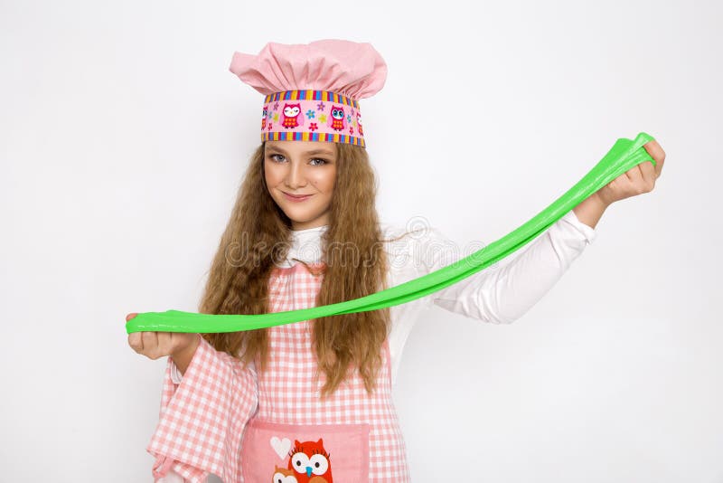 Милая смешная девушка с шламом в кухне Девушка варит и печет ее булочки, делает торт и шлам стоковые изображения rf Милая смешная девушка с шламом в кухне Девушка варит и печет ее булочки, делает торт и шлам стоковые изображения rf