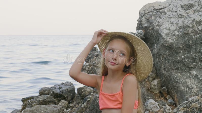 Cute teen girl in bikini trying a straw on a rock in sea water Portrait of a beautiful girl in a summer hat on the sea stock video - Video counting day, relax: 165353683     