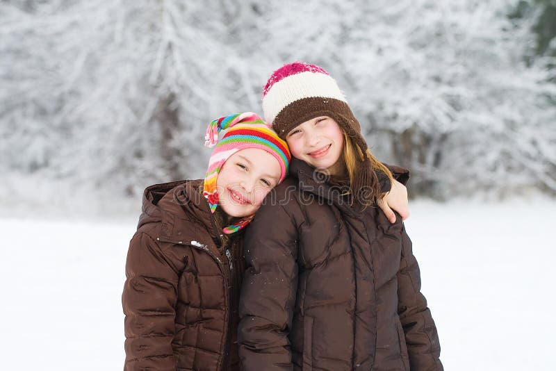 Two young children with happy expressions playing outside in the snow. Two young children with happy expressions playing outside in the snow.