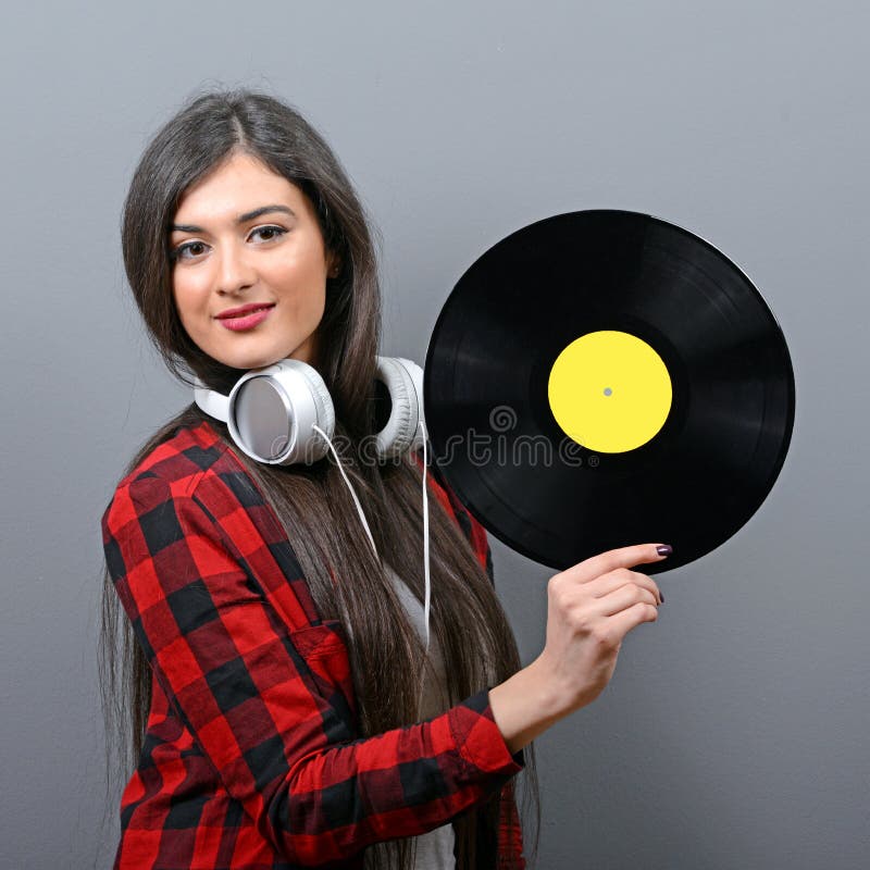 Милый женский DJ с наушниками и винилом против серой предпосылки стоковое фото rf Милый женский DJ с наушниками и винилом против серой предпосылки стоковое фото rf