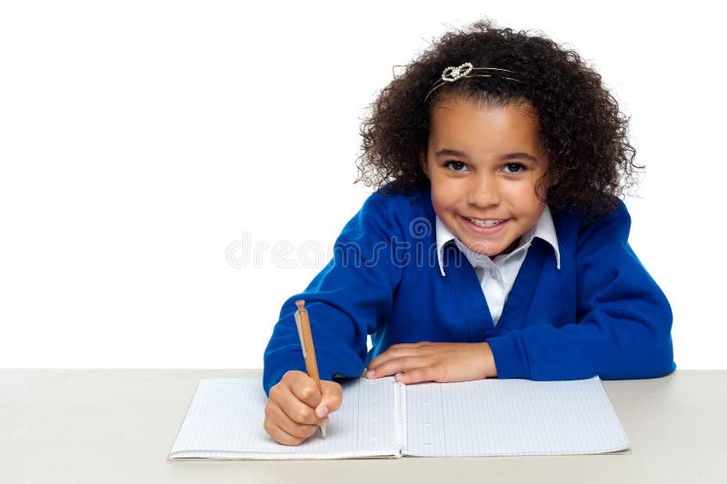 Studio shot of a cute primary kid writing her assignment. Studio shot of a cute primary kid writing her assignment.