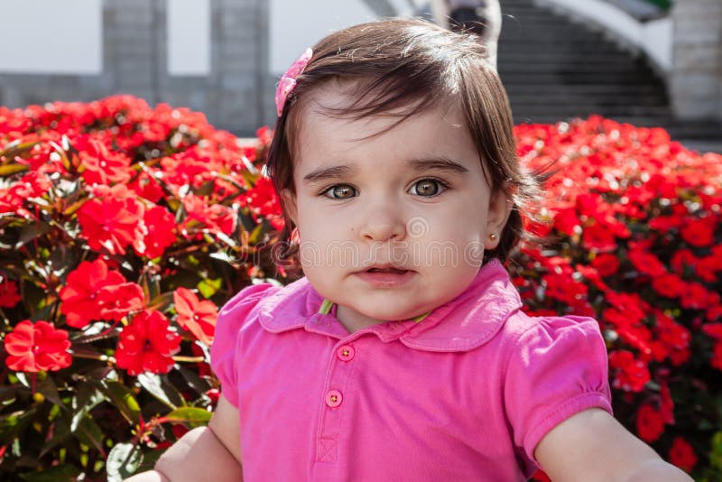 Cute, pretty, happy, chubby smiling toddler taking a selfie of herself in a garden of red flowers. Fourteen months old. Cute, pretty, happy, chubby smiling toddler taking a selfie of herself in a garden of red flowers. Fourteen months old