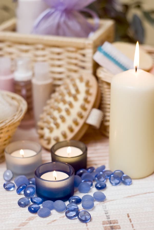 A spa composition with bath items and three blue candles in the foreground. A spa composition with bath items and three blue candles in the foreground.