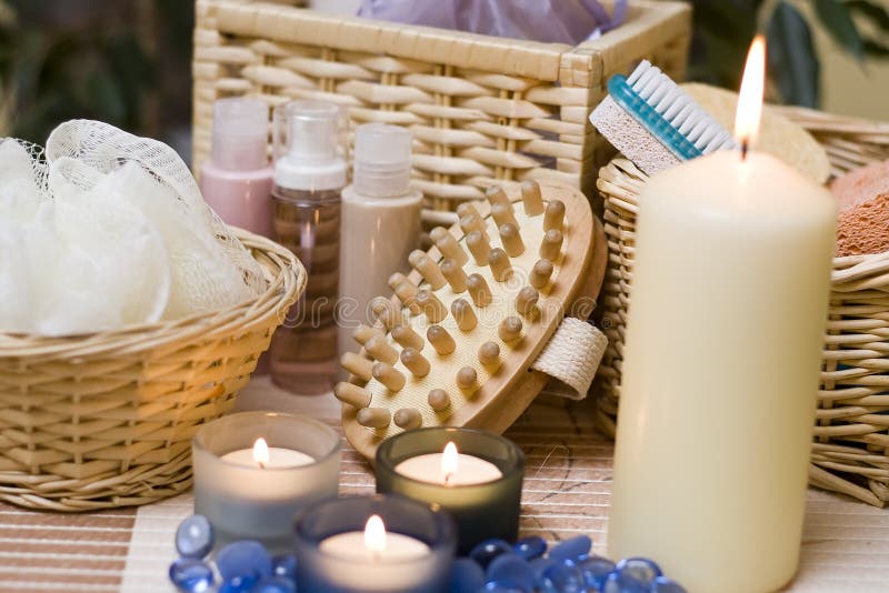 A spa composition with bath items and three blue candles in the foreground. A spa composition with bath items and three blue candles in the foreground.
