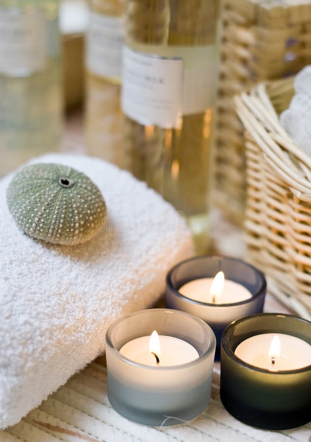 Beige spa composition, three small candles in the foreground, cosmetic bottles in the background blurred. Beige spa composition, three small candles in the foreground, cosmetic bottles in the background blurred.