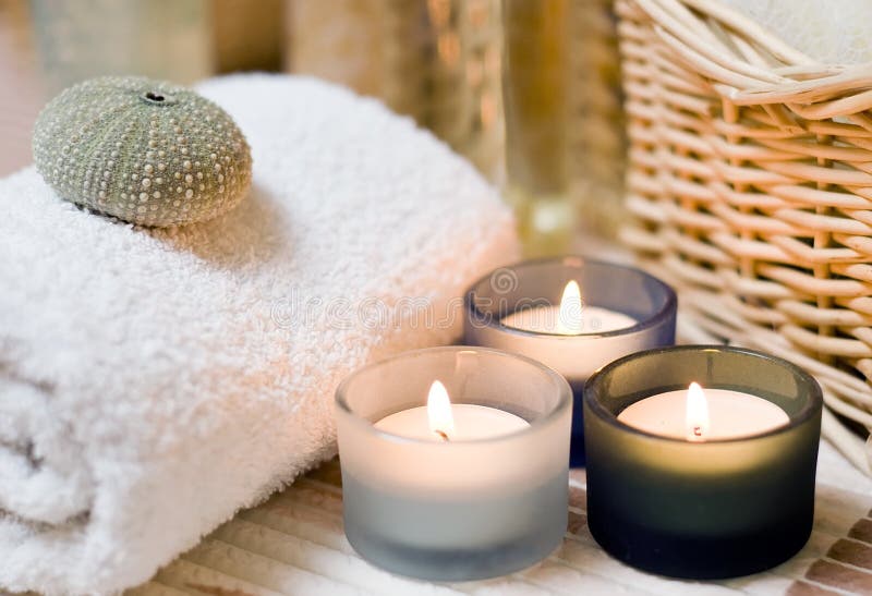 Beige spa composition, three small candles in the foreground, cosmetic bottles in the background blurred. Beige spa composition, three small candles in the foreground, cosmetic bottles in the background blurred.