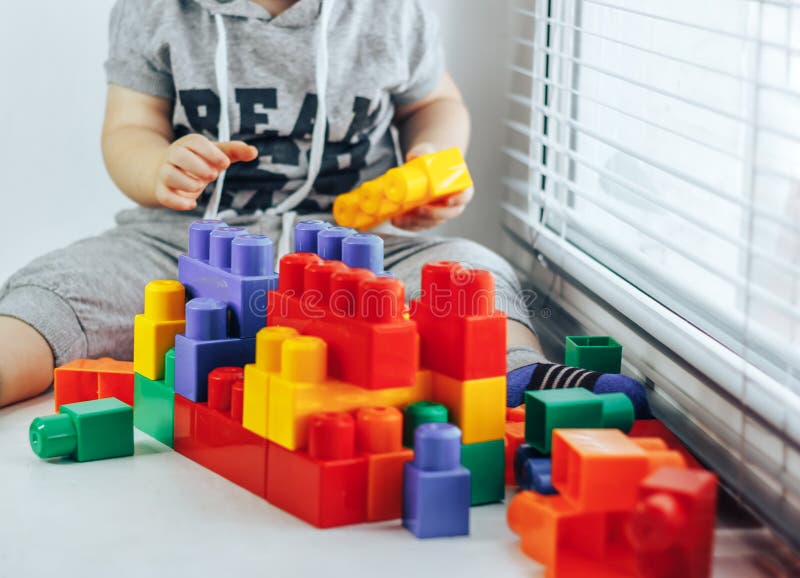 Младенец constructorLittle игры младенца играя с сериями красочной пластмассы преграждает конструктора около окна стоковая фотография Младенец constructorLittle игры младенца играя с сериями красочной пластмассы преграждает конструктора около окна стоковая фотография