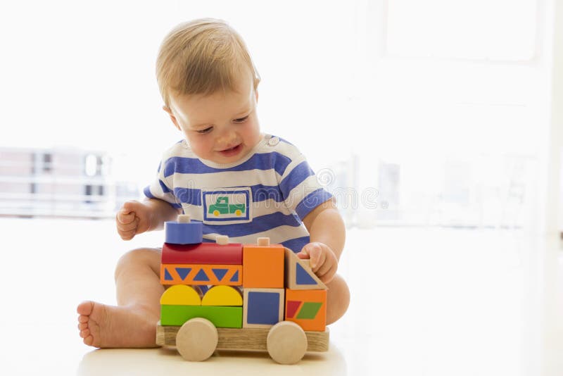 Baby indoors playing with truck on the floor. Baby indoors playing with truck on the floor