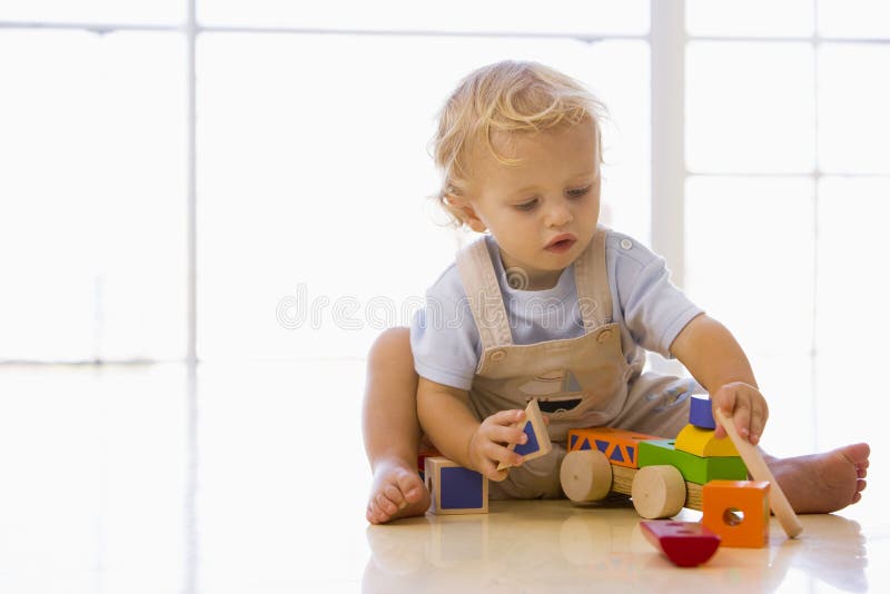 Baby indoors playing with toy truck on a wooden floor. Baby indoors playing with toy truck on a wooden floor