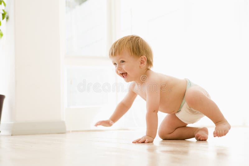Baby crawling indoors smiling away from camera. Baby crawling indoors smiling away from camera