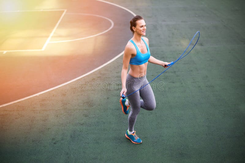 Молодая женщина в sportswear работая с прыгая веревочкой на стадионе стоковое фото rf Молодая женщина в sportswear работая с прыгая веревочкой на стадионе стоковое фото rf