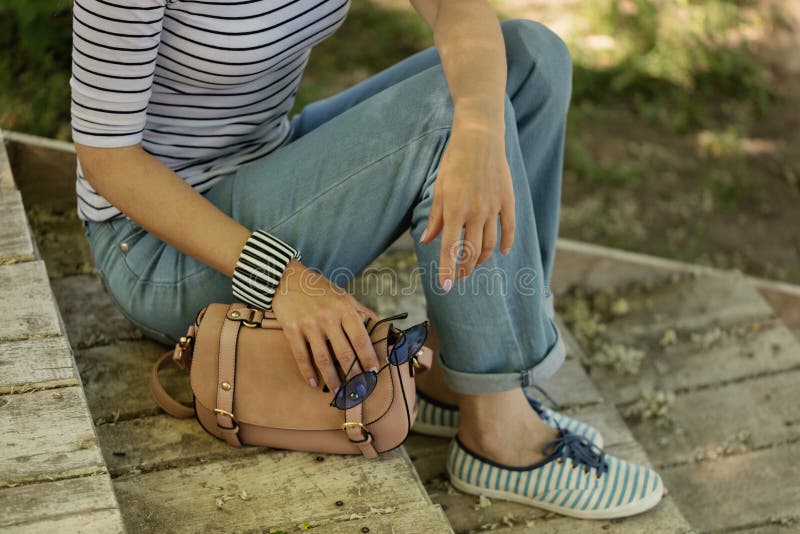 Молодая женщина в голубых джинсах, striped тапки сидит на старом деревянном s стоковая фотография rf