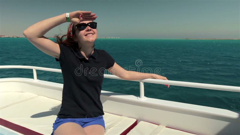 Молодая женщина в солнечных очках сидит на шлюпке яхты