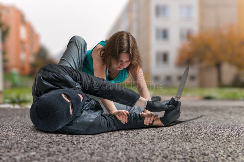 Young women is fighting with armed thief with knife. Self defense concept. Young women is fighting with armed thief with knife. Self defense concept.