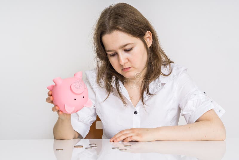 Молодая женщина не имеет никакие деньги Ее piggy банк денег с сбережениями пуст стоковые изображения