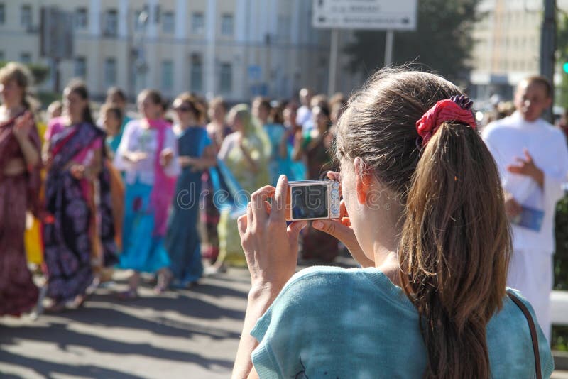 Молодая женщина фотографируя группу в составе зайцы Krishna стоковое изображение rf Молодая женщина фотографируя группу в составе зайцы Krishna стоковое изображение rf