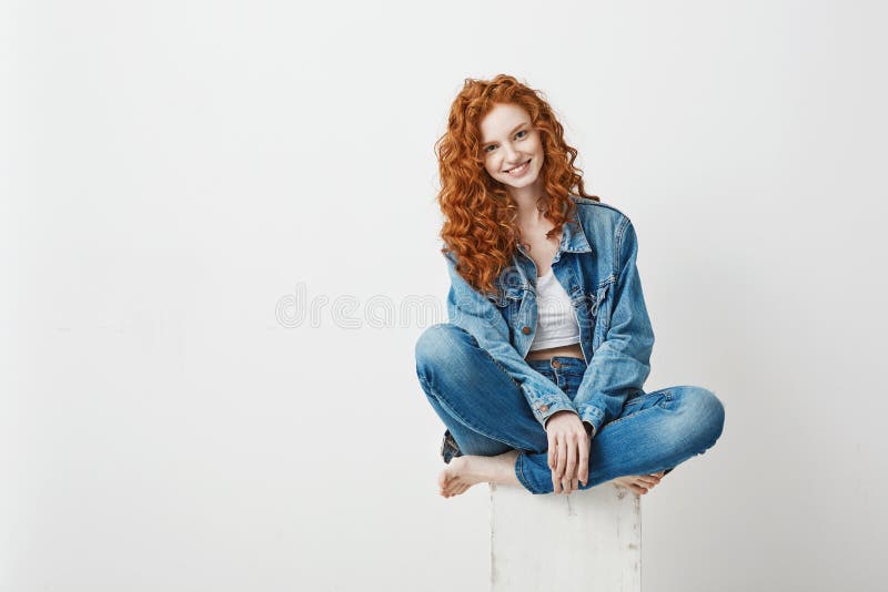 Молодая красивая девушка redhead усмехаясь смотрящ камеру сидя на коробке над белой предпосылкой скопируйте космос стоковые фото Молодая красивая девушка redhead усмехаясь смотрящ камеру сидя на коробке над белой предпосылкой скопируйте космос стоковые фото