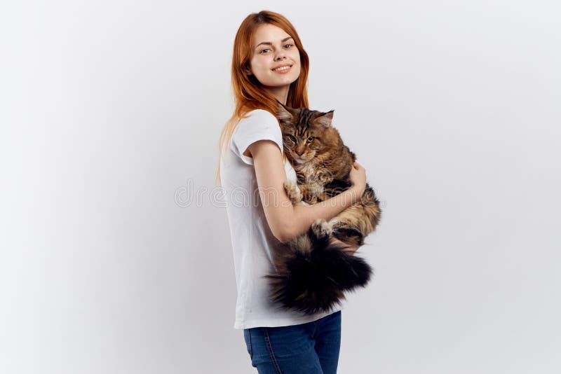 Молодая красивая женщина на белой предпосылке держит кота, улыбки, любимчиков стоковая фотография