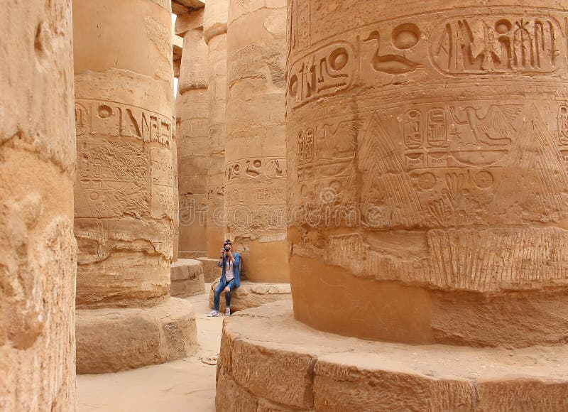 Молодая красивая женщина фотографируя между столбцами hypostyle залы виска Karnak в Луксоре, Египте стоковые фотографии rf Молодая красивая женщина фотографируя между столбцами hypostyle залы виска Karnak в Луксоре, Египте стоковые фотографии rf