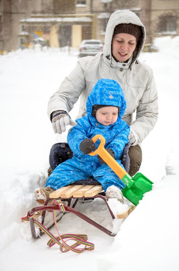 Молодая мать и мальчик наслаждаясь ездой саней Sledding ребенка Розвальни катания ребенк малыша Игра детей outdoors в снеге малыш стоковое изображение Молодая мать и мальчик наслаждаясь ездой саней Sledding ребенка Розвальни катания ребенк малыша Игра детей outdoors в снеге малыш стоковое изображение