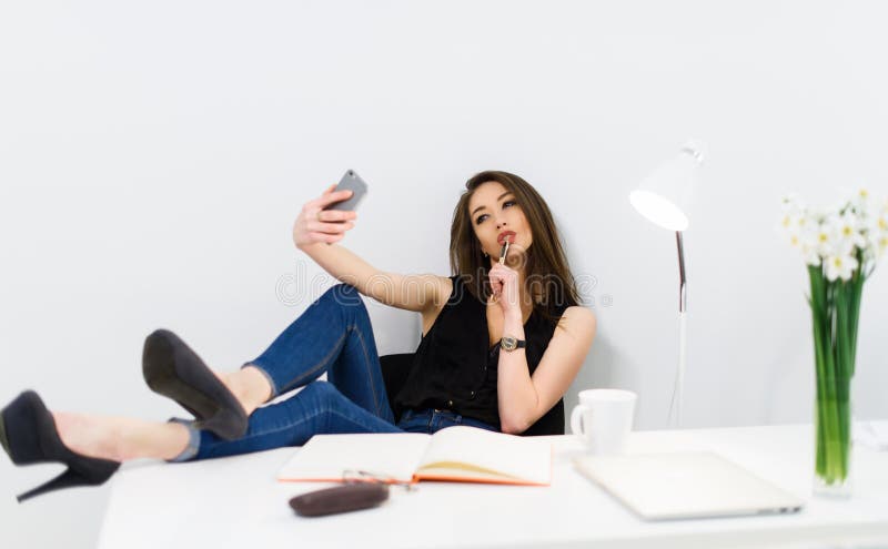 Молодая милая бизнес-леди на ее рабочем месте делая selfie стоковые изображения Молодая милая бизнес-леди на ее рабочем месте делая selfie стоковые изображения