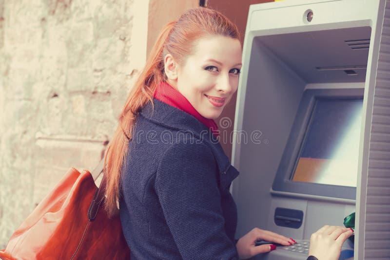 Молодая счастливая женщина используя ATM стоковые фотографии rf Молодая счастливая женщина используя ATM стоковые фотографии rf