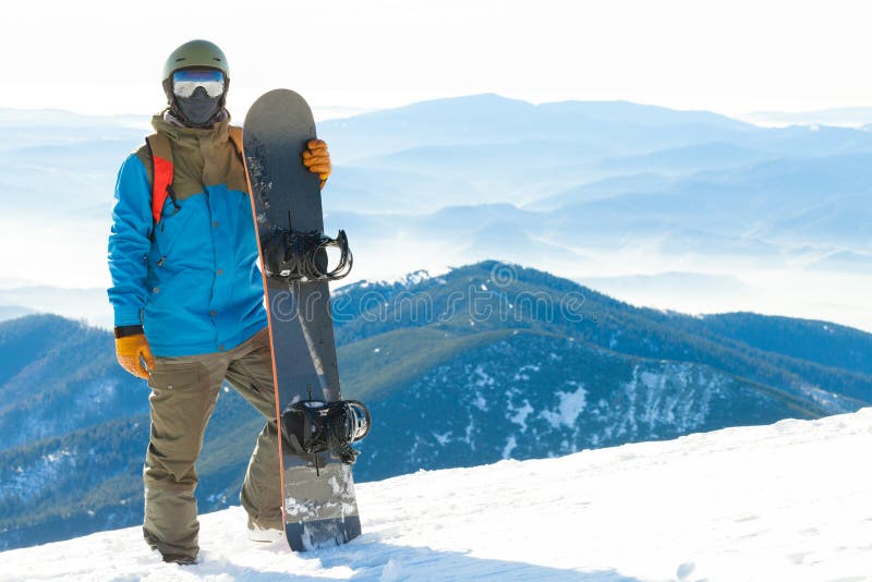 Молодой snowboarder стоя рядом с сноубордом толкнул в снег с красивым пейзажем на предпосылке стоковое изображение Молодой snowboarder стоя рядом с сноубордом толкнул в снег с красивым пейзажем на предпосылке стоковое изображение