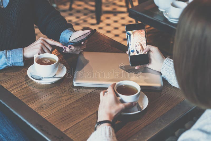 2 молодой женщины сидя на таблице в кафе и используя smartphones Ходить по магазинам девушек онлайн стоковые изображения rf 2 молодой женщины сидя на таблице в кафе и используя smartphones Ходить по магазинам девушек онлайн стоковые изображения rf
