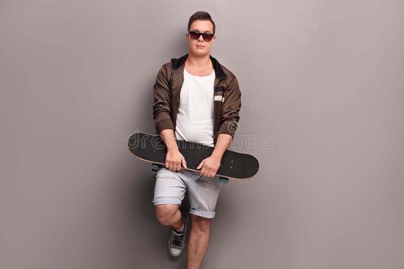 Молодой мужской конькобежец держа скейтборд