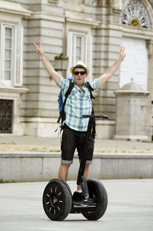 Молодой счастливый туристский человек с путешествием города катания рюкзака segway управляющ счастливым и excited посещая дворцом стоковые фото