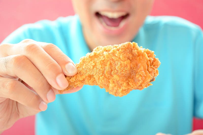 Молодой человек есть глубокие ногу или drumstick жареной курицы стоковое фото rf