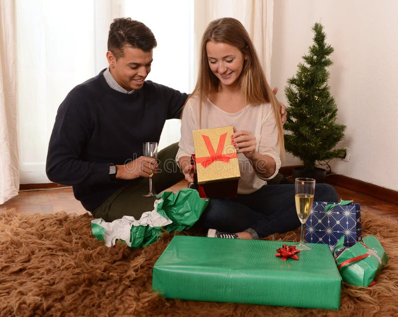 Молодые счастливые пары раскрывая настоящие моменты Xmas стоковая фотография rf