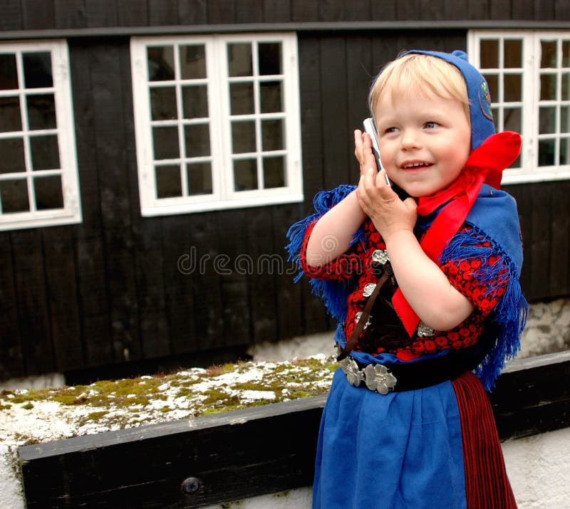 Baby girl (2 y.o.) in Faroese national costume using a mobile phone during St. Olaf's Days (the national holidays). Baby girl (2 y.o.) in Faroese national costume using a mobile phone during St. Olaf's Days (the national holidays).