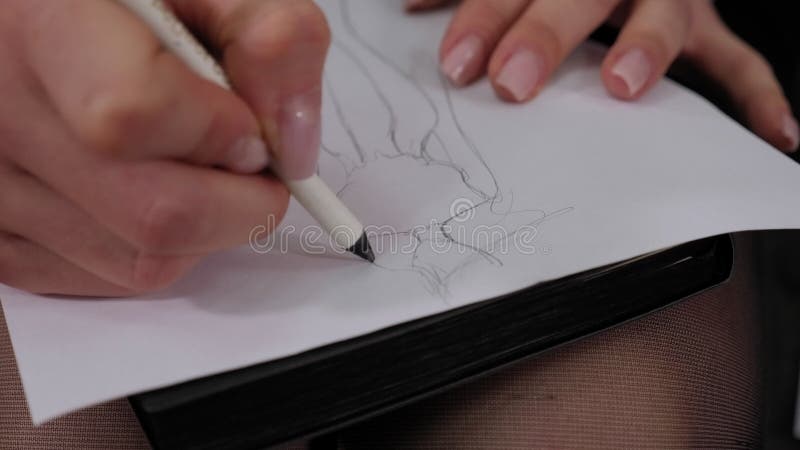 модельер рисует эскиз платья карандашом на бумаге.