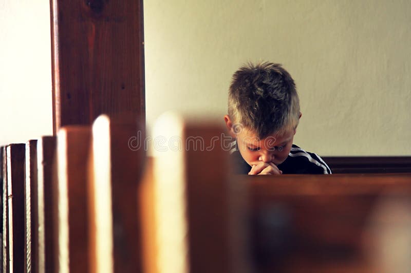 The little boy is praying in the church. The little boy is praying in the church
