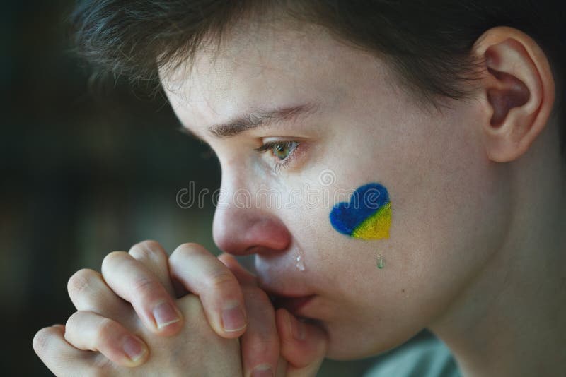 молодая грустная женщина с символом украинского флага на её лице плачет стоковое фото rf