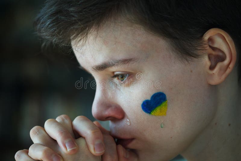 молодая грустная женщина с символом украинского флага на лице плачет, остановить войну стоковые фото