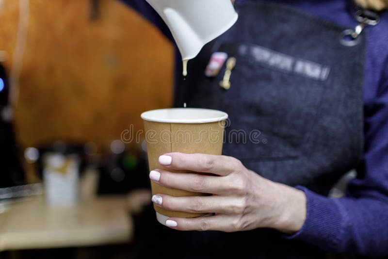 Молодая девушка barista лить стекло капучино стоковые изображения Молодая девушка barista лить стекло капучино стоковые изображения
