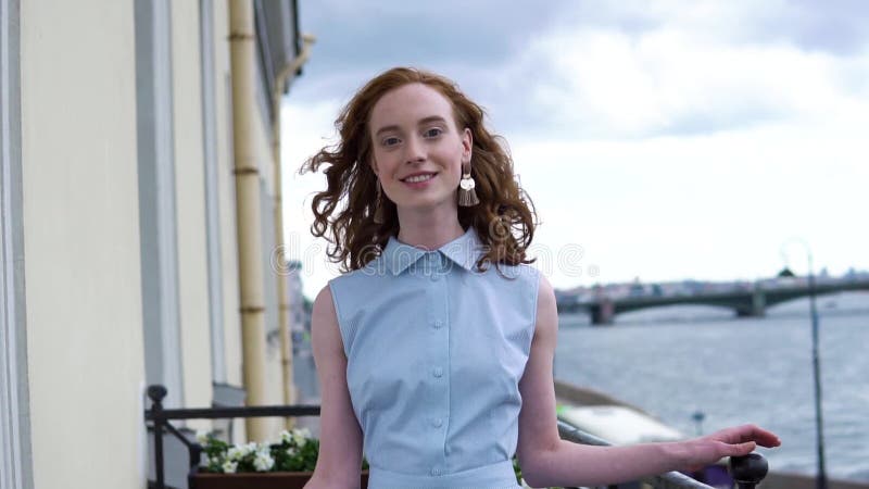 Молодая девушка redhead в голубом платье представляя на камере на балконе акции видеоматериалы