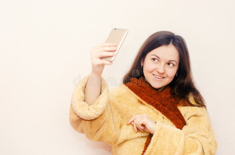 Молодая девушка брюнет в купальном халате делает selfie стоковые изображения rf Молодая девушка брюнет в купальном халате делает selfie стоковые изображения rf