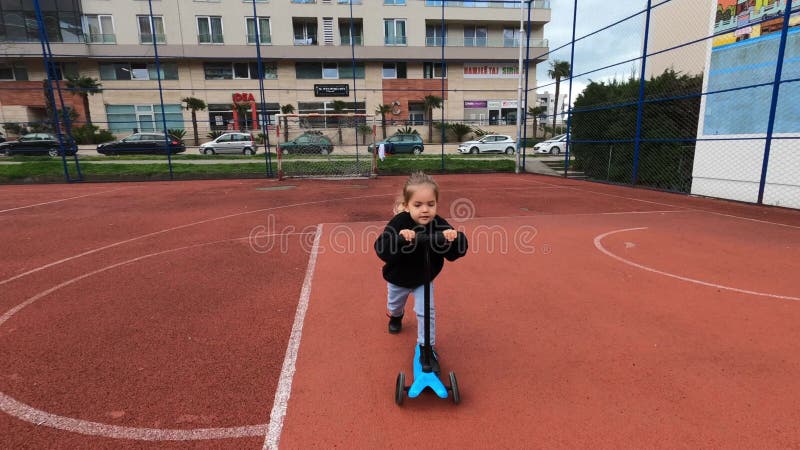 молодая девушка наслаждается отдыхом верхом на скутере на баскетбольной площадке