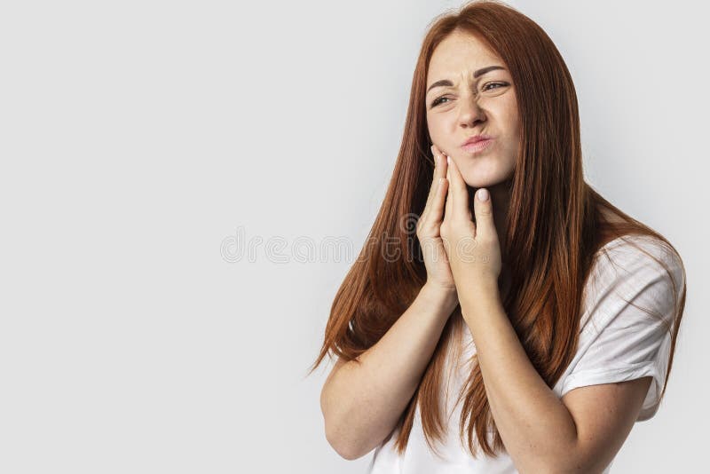 Молодая женщина redhead изолированная на серой предпосылке касаясь ее стороне и с выражением ужасного страдает от проблемы здоров стоковое изображение Молодая женщина redhead изолированная на серой предпосылке касаясь ее стороне и с выражением ужасного страдает от проблемы здоров стоковое изображение