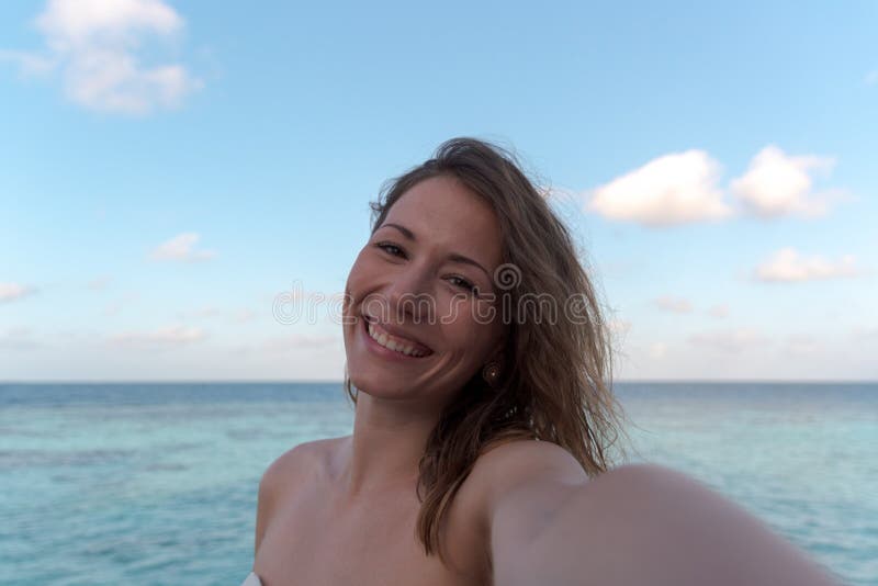 Молодая женщина в медовом месяце принимая selfie Море как предпосылка стоковая фотография rf Молодая женщина в медовом месяце принимая selfie Море как предпосылка стоковая фотография rf
