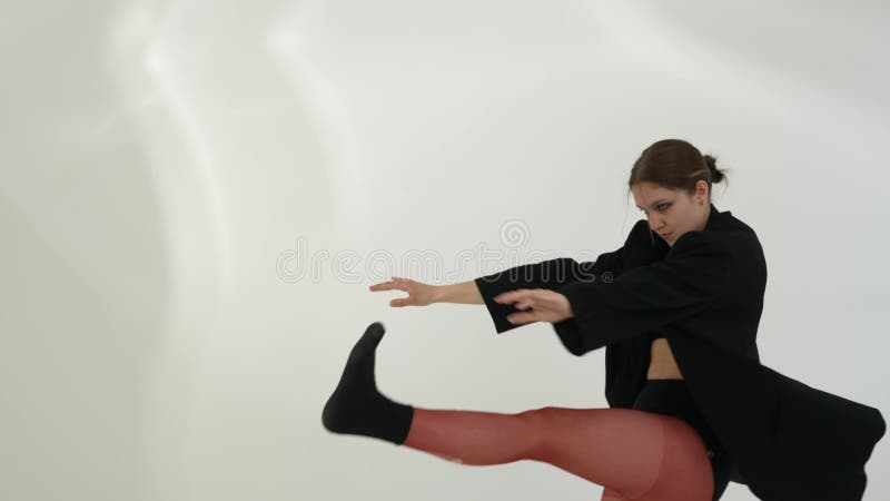 Молодая женщина в черной одежде, танцующая современник на белом фоне акции видеоматериалы
