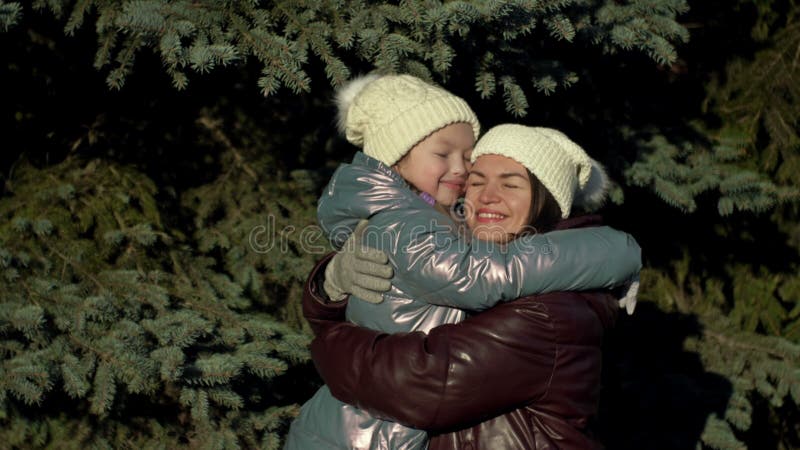 молодая женщина и ее дочь 78 лет смотрят друг на друга с любовью и нежностью. в зимнем лесу сток-видео