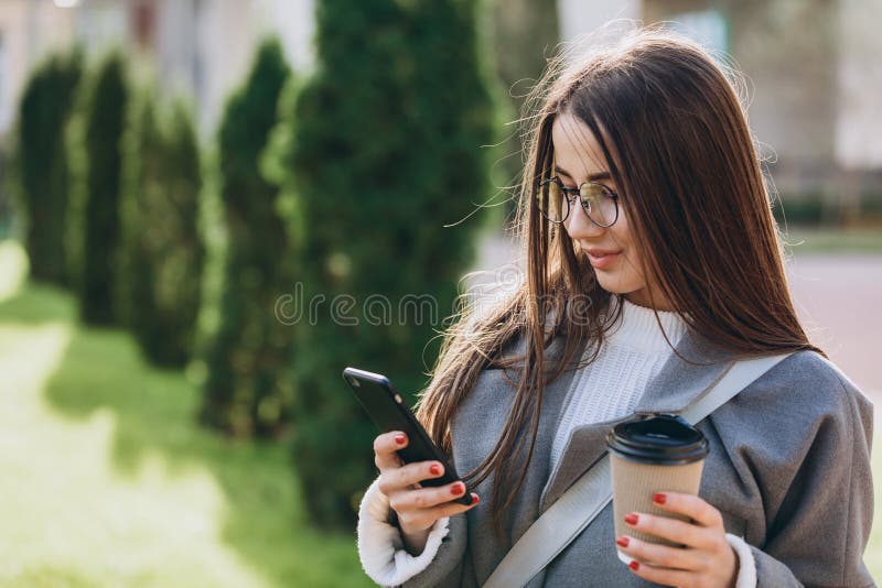 Молодая женщина отправляя SMS или используя смартфону стоковая фотография rf Молодая женщина отправляя SMS или используя смартфону стоковая фотография rf