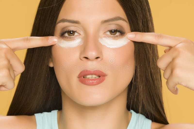Молодая женщина, применяя creme на низких веках стоковые фотографии rf